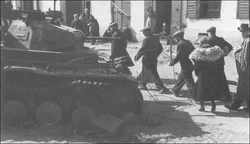 Citizens of Plzeň walks past a destroyed Pz.Kpfw. II Ausf. C light tank of the 1. Panzer-Division following the failed assault on the Plzeň suburb of Božkov on October 25, 1938.
