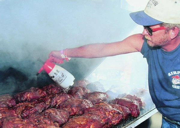 A member of the Airpork Crew barbecue team prepares pork shoulder at the Memphis in May World Championship Barbecue Cooking Contest.