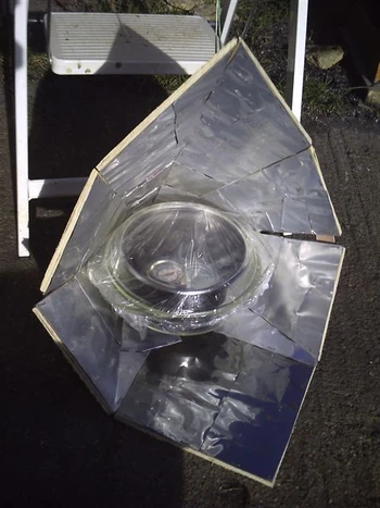 A funnel cooker made out of wood, using old beer and drink cans (cut open, flattened and then stapled to the wood) as reflectors
