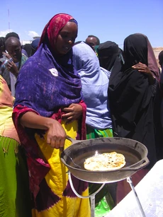 A woman involved with the Sun Fire Cooking project cooks flatbread in a parabolic solar cooker in Somalia.