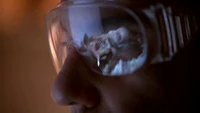 A dissected baby alien is reflected in a doctor's goggles.