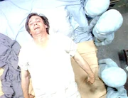 Surrounded by alien beings, Barry floats above his bed